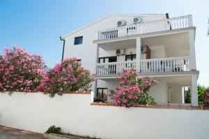 ein weißes Gebäude mit rosa Blumen an einer weißen Wand in der Unterkunft Villa Dusper in Trogir