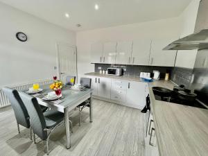 a kitchen with a table and chairs in a kitchen at Cheerful 3-bedroom Near Bikepark Wales Merthyr Tydfil Town Centre in Merthyr Tydfil