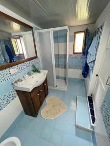 een blauwe en witte badkamer met een wastafel en een douche bij B&B Marino in Grisolia