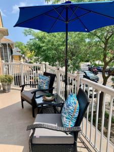 a patio with two chairs and a blue umbrella at Suites On King in Niagara on the Lake