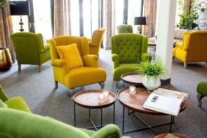 a living room with yellow and green chairs and tables at Rosendomizil Klein Venedig in Malchow