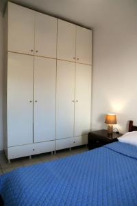 a bedroom with a blue bed and white cabinets at Yiampanaki in Vasiliki