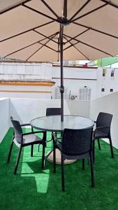 uma mesa e cadeiras com um guarda-sol na relva em Apartamentos centro histórico em Sevilha