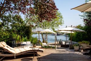 a patio with couches and umbrellas next to the water at Rosendomizil Klein Venedig in Malchow