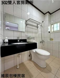 uma casa de banho com um WC, um lavatório e um espelho. em 維辰包棟民宿Wei Chen Resort B&B em Xiaoliuqiu