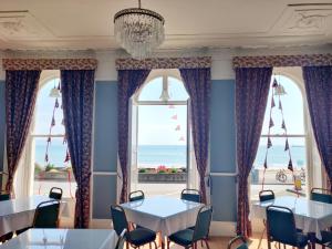 a dining room with tables and chairs and a large window at The Lawrence of Arabia Hotel in Weymouth