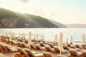 a bunch of chairs and umbrellas on a beach at Enjoy Lichnos Bay Village, Camping, Hotel and Apartments in Parga