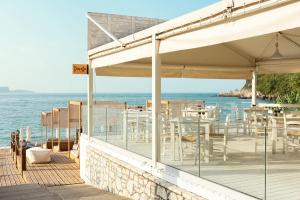 un restaurante en la playa con mesas y sillas en Enjoy Lichnos Bay Village, Camping, Hotel and Apartments en Párga