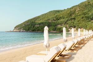 a row of white lounge chairs on a beach at Enjoy Lichnos Bay Village, Camping, Hotel and Apartments in Parga