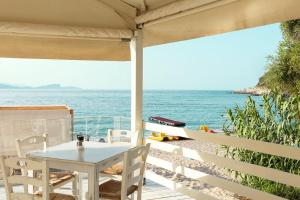 a table and chairs on a deck with the ocean at Enjoy Lichnos Bay Village, Camping, Hotel and Apartments in Parga