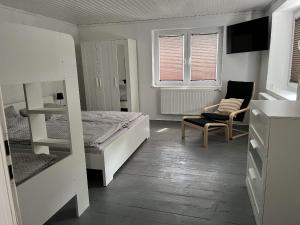 1 dormitorio con 1 cama, 1 silla y ventanas en Alte Mühle - Ferienwohnung Betti, en Herdwangen-Schönach