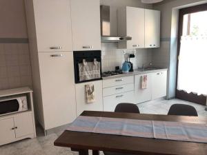 uma cozinha com armários brancos e uma mesa com cadeiras em Casa in centro Domodossola self check in em Domodossola