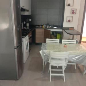 uma cozinha com uma mesa e cadeiras e um frigorífico em Bel Appartement Tamourit Agadir em Agadir
