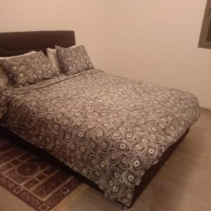 uma cama com um edredão e almofadas num quarto em Bel Appartement Tamourit Agadir em Agadir