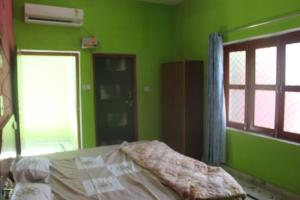 Un dormitorio con una cama con paredes verdes y una ventana en Down Town Homestay, en Khajurāho