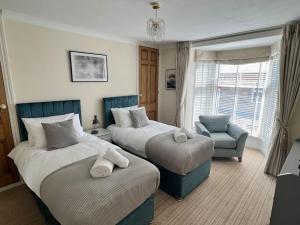 a bedroom with two beds and a chair and a window at Room 2, Hotel style twin bedroom in Marazion in Marazion