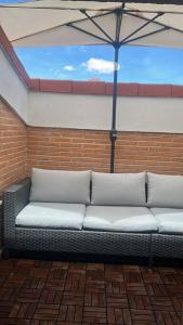 eine Couch, die an einer Backsteinwand mit einem Regenschirm sitzt in der Unterkunft Ático a 8 minutos de Toledo y 15 del Puy Du Fou in Bargas