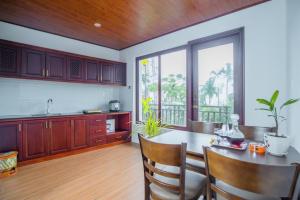 a kitchen with a table and chairs and a large window at SenDa Villa & Apartment Hoi An in Hoi An