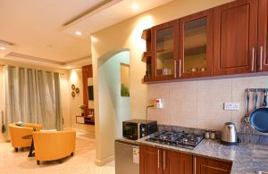 a kitchen with a stove top oven next to a living room at Premier Suites Kyanja in Kampala