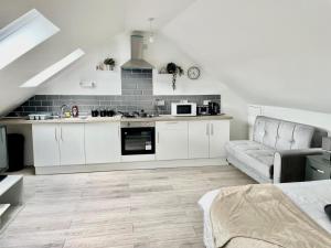 una cocina con armarios blancos y un sofá en una habitación en Exec 1-Bedroom Studio Apartment Briton Ferry, Neath Port Talbot 5, en Briton Ferry
