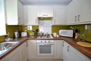 a kitchen with white cabinets and a wooden counter top at Cosy 2-Bedroom Cottages in Central Windsor in Windsor
