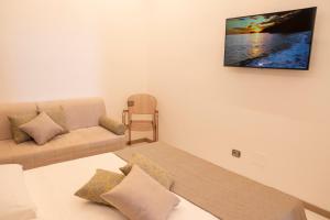uma sala de estar com um sofá e uma televisão na parede em BelMa' Aparthotel and Rooms em Marina di Camerota