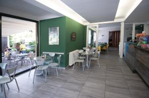 a restaurant with green walls and tables and chairs at Green Village Accommodations in Colico