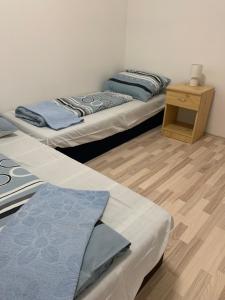 two beds in a room with a wooden floor at Apartmány JG Patince in Patince