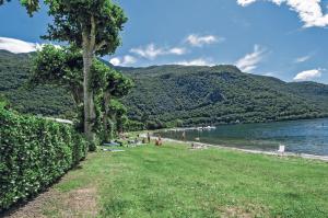 a beach with people laying on the grass next to the water at Green Village Accommodations in Colico
