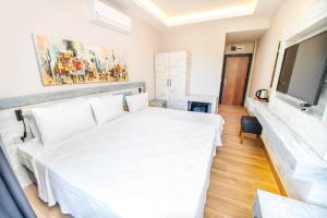達特恰的住宿－Feri Surf Club Hotel Datça，卧室配有白色的床和电视