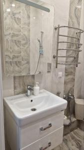 La salle de bains est pourvue d'un lavabo blanc et d'une douche. dans l'établissement Апартаменты в ЖК Bi city TOKYO, à Astana