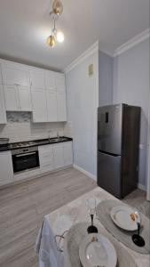 La cuisine est équipée d'une table et d'un réfrigérateur en acier inoxydable. dans l'établissement Апартаменты в ЖК Bi city TOKYO, à Astana