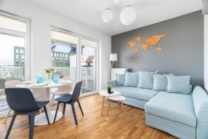 uma sala de estar com um sofá azul e uma mesa em Apartments Poznań Niedziałkowskiego by Renters em Poznań