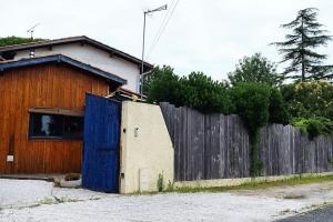 een gebouw met een blauwe deur naast een hek bij A la petite maison in Arès