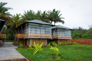 atropical house with a balcony and palm trees at Blue Ocean The Fern Resort & Spa Ganpatipule in Ganpatipule