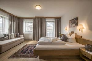 um quarto de hotel com uma cama e um sofá em Haus Alpin em Ellmau