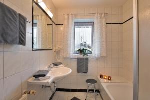 een witte badkamer met een wastafel en een bad bij Haus Alpin in Ellmau