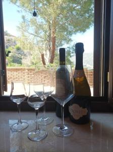 3 verres à vin et des bouteilles sur une table avec une fenêtre dans l'établissement A Casa da Nonna Brasa Holiday Home Savoca, à Savoca