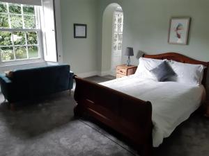 a bedroom with a bed and a chair and two windows at Reenglas House in Valentia Island