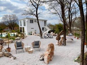 a patio with chairs and trees and a house at The Rock Stars Villa With Private Pool And Beach in Danilovgrad