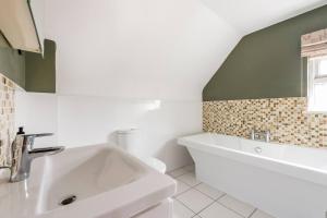 y baño blanco con lavabo y bañera. en Room in Guest room - Calm For 3, Handy For Airporttrain Free Parking en Bishops Stortford