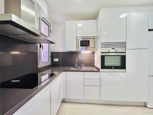 eine Küche mit weißen Schränken und Küchengeräten aus Edelstahl in der Unterkunft Apartamento Rambla Vella in Tarragona