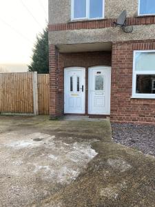 a brick house with a white door and a fence at 3 Room Apartment - Twinsdouble in Kings Lynn