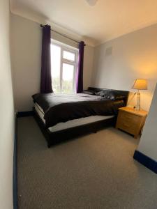 a bedroom with a bed and a window with purple curtains at 3 Room Apartment - Twinsdouble in Kings Lynn