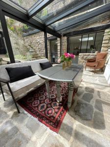 une terrasse avec une table et un canapé sur un tapis dans l'établissement Maison de caractère ST GOUSTAN, à Auray