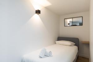 um pequeno quarto com uma cama branca e um espelho em DIFY Mazenod - Prefecture em Lyon