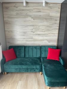 a green couch with two red pillows in a living room at Apartament Boston Jastrzębia Góra in Jastrzębia Góra