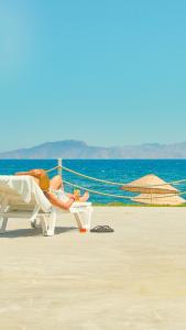 a woman laying on a chair on the beach at Feri Surf Club Hotel Datça in Datca