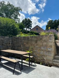 a picnic table and bench next to a stone wall at Maison Comtale in Rochefort