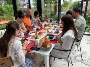 un grupo de personas sentadas alrededor de una mesa comiendo comida en Les Suites Champenoises, en Reims
